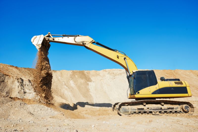 yellow excavator moving sand