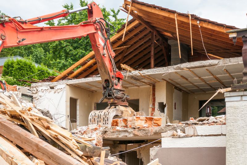 a red excavator pulling apart a house